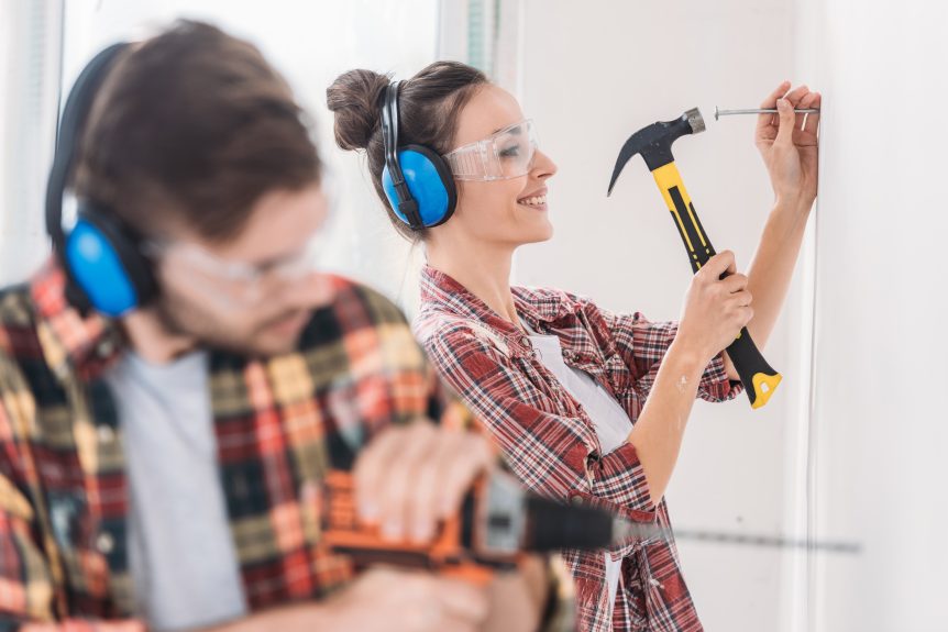 Young couple hammering and drilling house